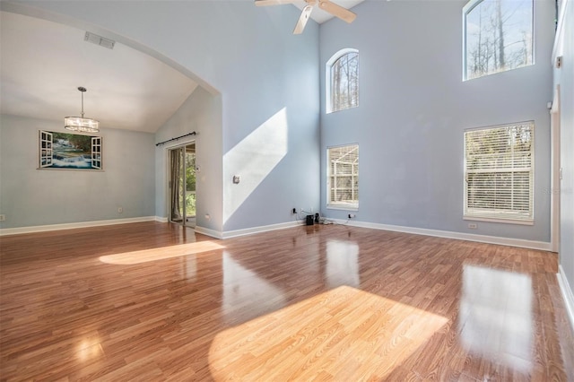 unfurnished living room with a high ceiling, ceiling fan, and light hardwood / wood-style flooring