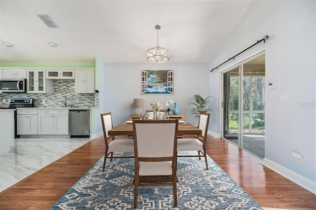 dining area with sink, a chandelier, and light wood-type flooring