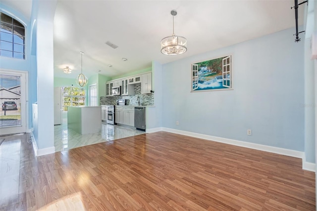 unfurnished living room featuring a notable chandelier, light hardwood / wood-style floors, and sink