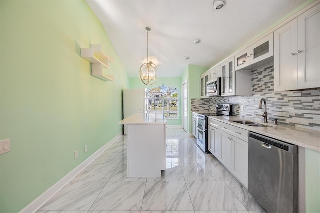 kitchen with sink, appliances with stainless steel finishes, white cabinetry, a center island, and decorative backsplash