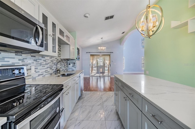 kitchen featuring sink, decorative light fixtures, gray cabinets, a notable chandelier, and stainless steel appliances