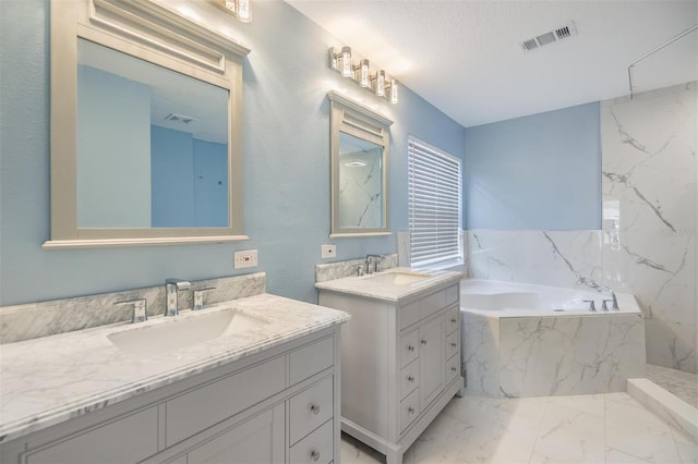 bathroom with vanity, tiled bath, and a textured ceiling