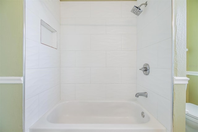 bathroom featuring tiled shower / bath and toilet