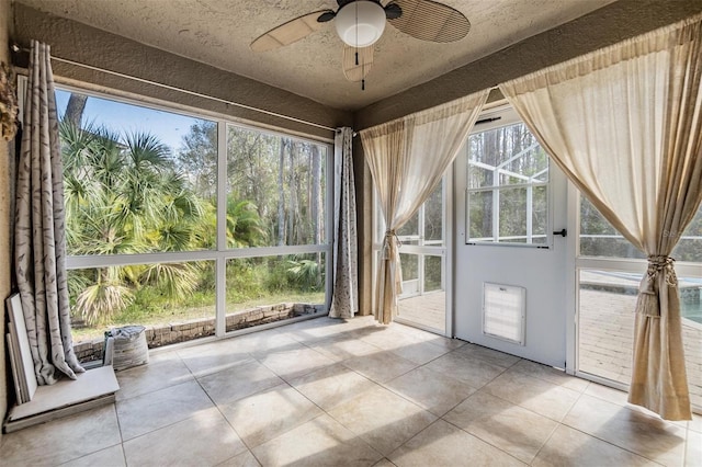 unfurnished sunroom featuring ceiling fan and a wealth of natural light