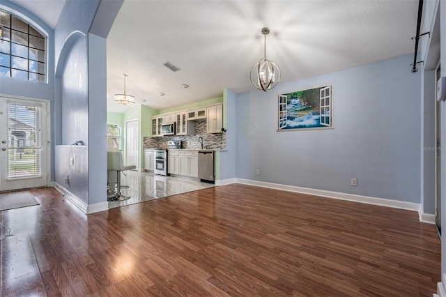 212 Arbor Woods Cir, Oldsmar, FL 34677 - unfurnished living room with a notable chandelier, baseboards, visible vents, arched walkways, and wood finished floors
