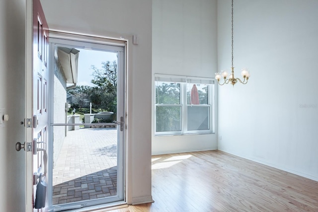 doorway to outside with plenty of natural light, a chandelier, and light wood-type flooring