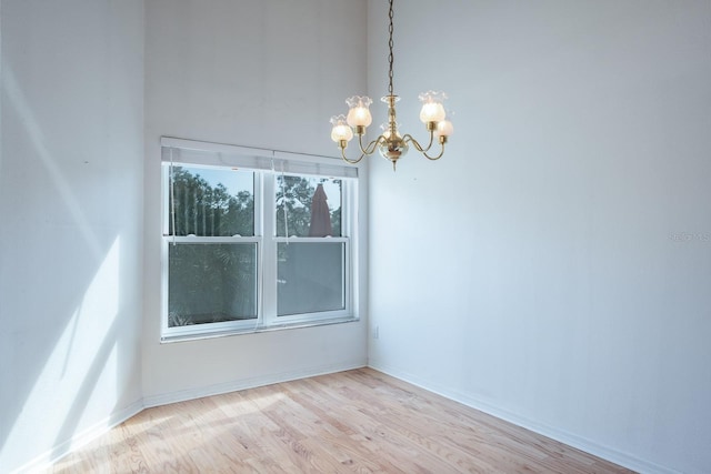 empty room with an inviting chandelier and light hardwood / wood-style floors