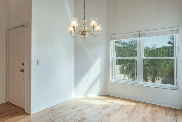 empty room with an inviting chandelier and light hardwood / wood-style floors