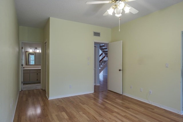 empty room with ceiling fan, a textured ceiling, and light wood-type flooring