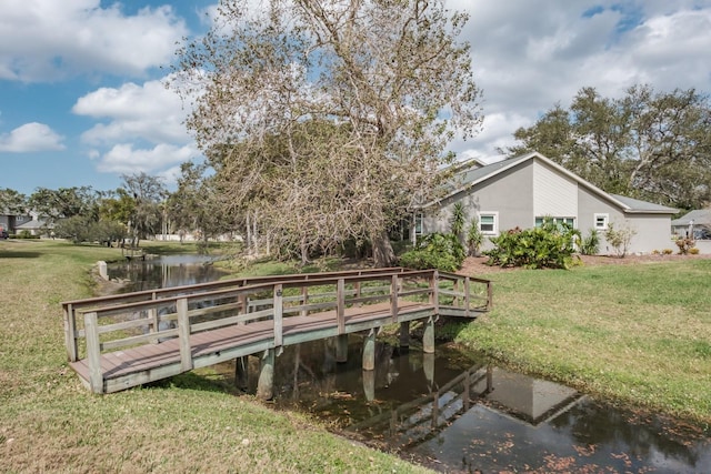 view of dock featuring a lawn and a water view