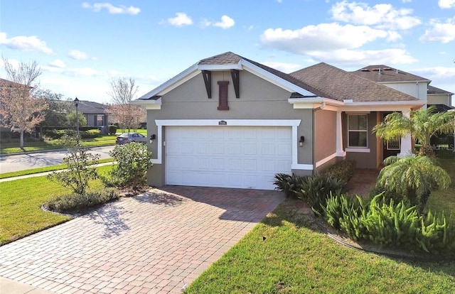 ranch-style home featuring an attached garage, a front yard, decorative driveway, and stucco siding