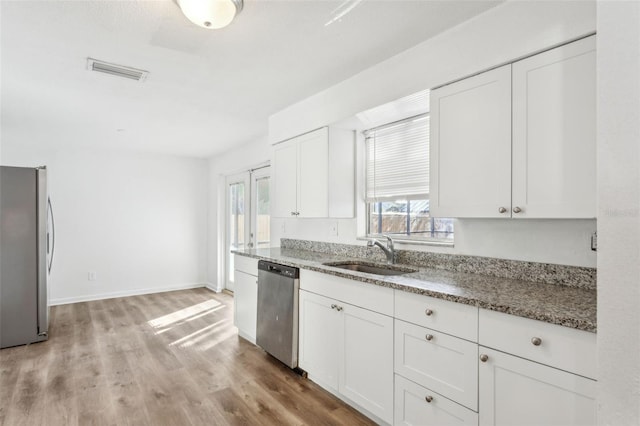 kitchen with sink, white cabinetry, stone countertops, a wealth of natural light, and stainless steel appliances