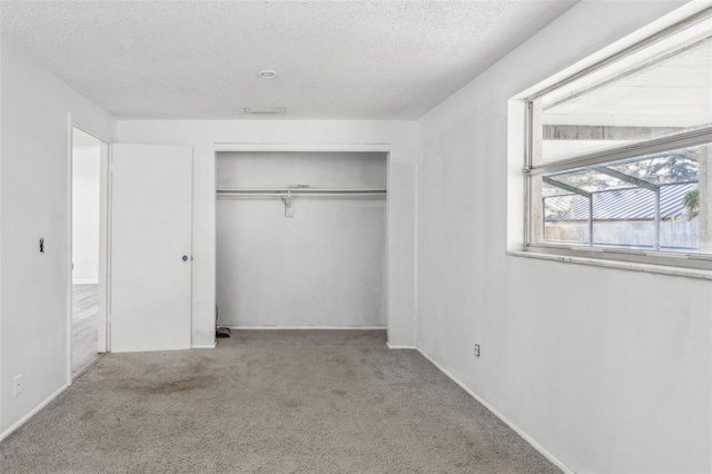 unfurnished bedroom with light carpet, a textured ceiling, and a closet