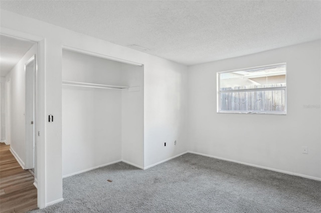 unfurnished bedroom with carpet floors, a closet, and a textured ceiling