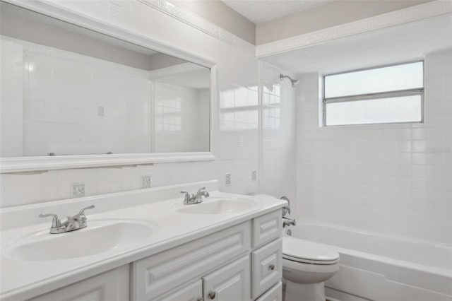 full bathroom with vanity, tiled shower / bath combo, a textured ceiling, and toilet