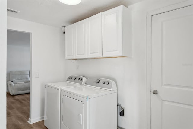 laundry room featuring cabinets, independent washer and dryer, and wood-type flooring