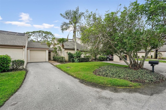 view of front of house with an attached garage, a front yard, stucco siding, and aphalt driveway