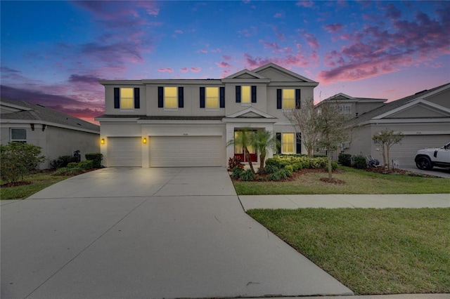 traditional-style house featuring driveway, a yard, an attached garage, and stucco siding