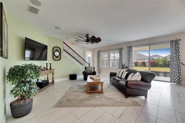 living area with visible vents, stairway, light tile patterned flooring, a textured ceiling, and baseboards