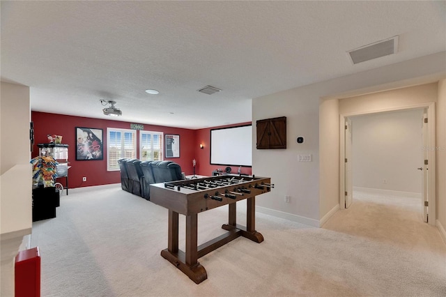 recreation room with light colored carpet, visible vents, a textured ceiling, and baseboards