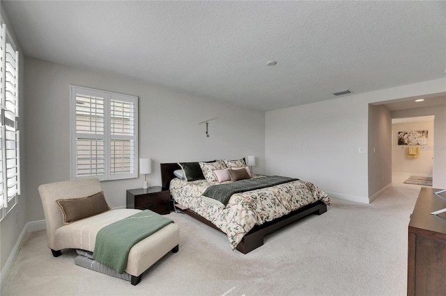 bedroom featuring a textured ceiling, carpet flooring, visible vents, and baseboards