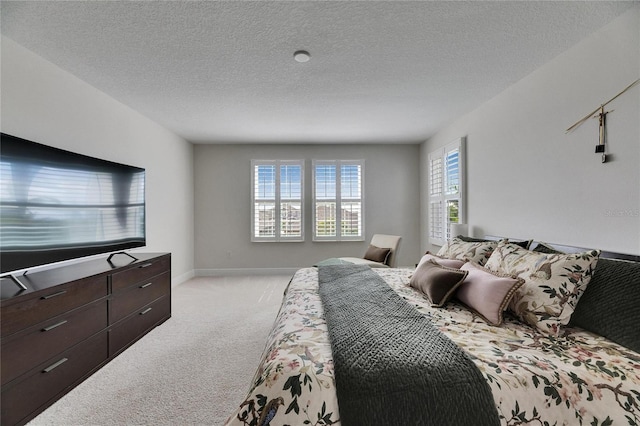 bedroom with baseboards, a textured ceiling, and light colored carpet