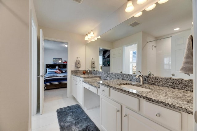 ensuite bathroom with tile patterned flooring, a sink, visible vents, tiled shower, and double vanity