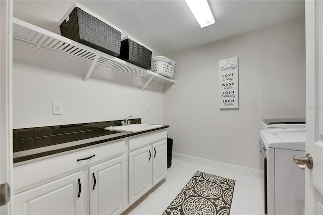 washroom with light tile patterned floors, baseboards, washer and clothes dryer, a textured ceiling, and a sink