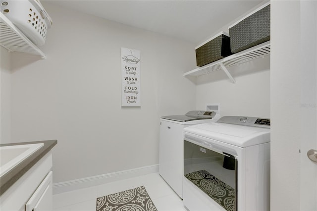 laundry room with light tile patterned floors, laundry area, washing machine and dryer, and baseboards