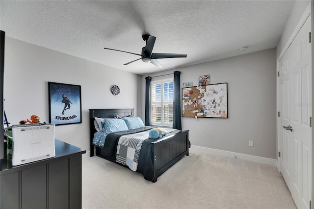 bedroom featuring baseboards, light colored carpet, ceiling fan, a textured ceiling, and a closet