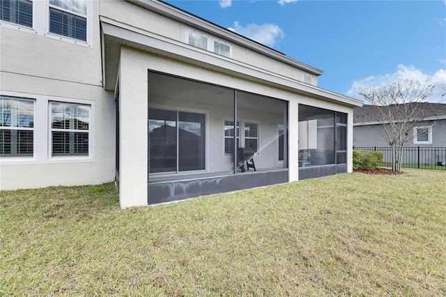 back of property featuring a yard, fence, a sunroom, and stucco siding