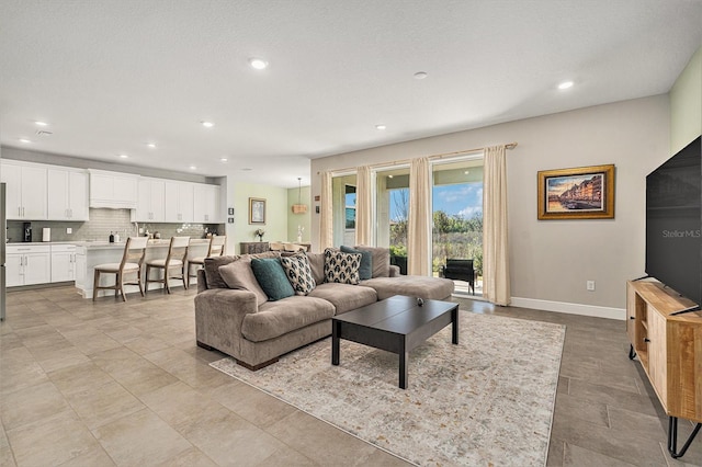 living area with recessed lighting, a textured ceiling, and baseboards