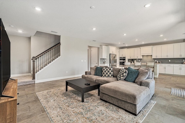 living room featuring visible vents, baseboards, stairs, a textured ceiling, and recessed lighting