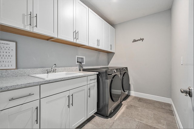clothes washing area with cabinet space, baseboards, washer and clothes dryer, and a sink