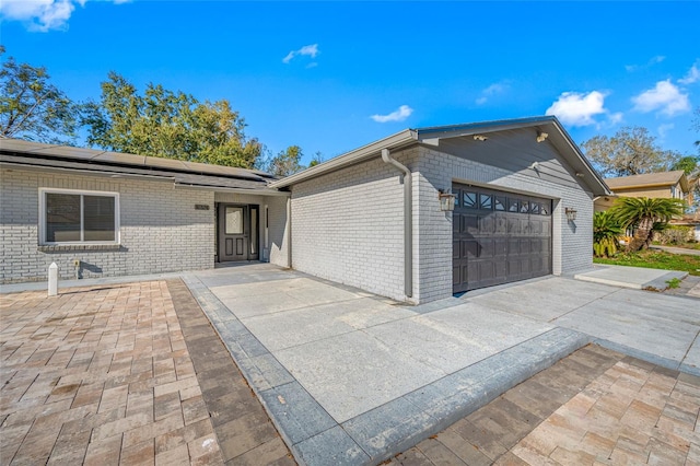 ranch-style home with a garage and solar panels