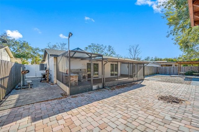 rear view of house with a lanai, a sunroom, and a patio