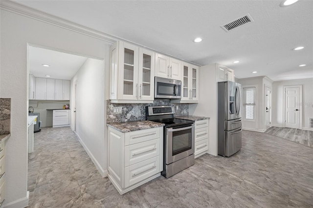 kitchen with dark stone countertops, decorative backsplash, white cabinets, and appliances with stainless steel finishes