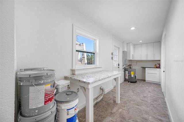 kitchen with water heater, light stone countertops, a breakfast bar, and white cabinets