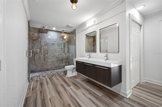 bathroom featuring toilet, a shower with shower door, a textured ceiling, vanity, and hardwood / wood-style floors