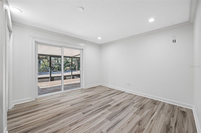 empty room with ornamental molding, a textured ceiling, and light wood-type flooring