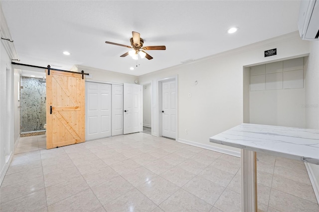 interior space with ornamental molding, a barn door, and ceiling fan