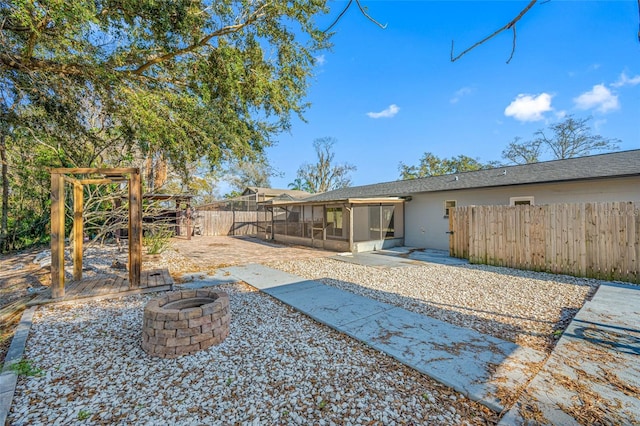 view of yard with a sunroom, a patio area, and a fire pit