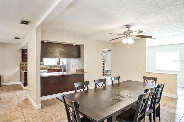 dining space featuring ceiling fan, sink, light tile patterned floors, and a textured ceiling