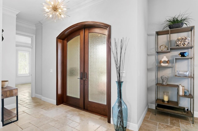 foyer featuring an inviting chandelier, ornamental molding, and french doors