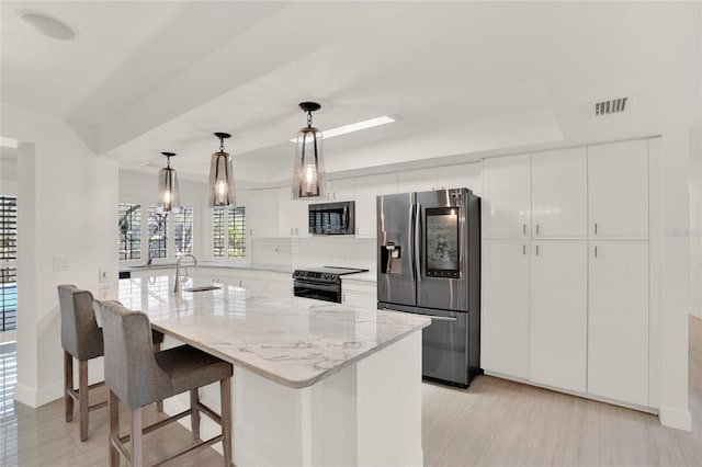 kitchen with sink, white cabinetry, a kitchen island with sink, stainless steel appliances, and decorative light fixtures