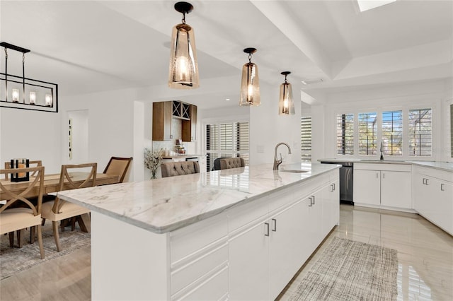 kitchen featuring decorative light fixtures, dishwasher, white cabinetry, sink, and a kitchen island with sink