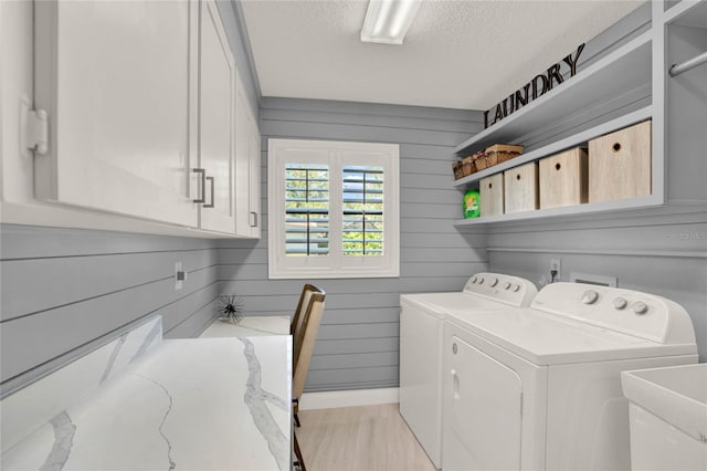 washroom featuring sink, cabinets, a textured ceiling, wooden walls, and washer and clothes dryer