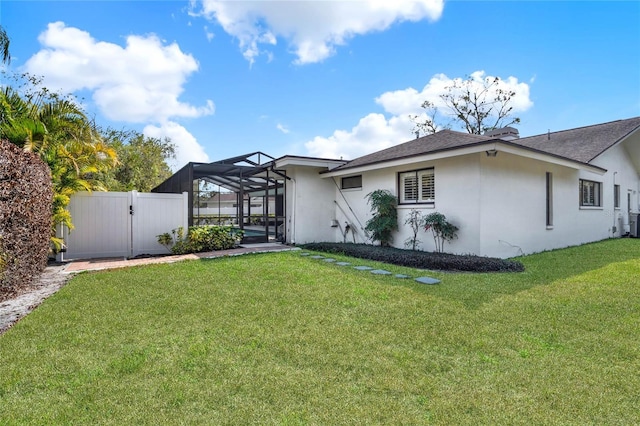 rear view of house with a yard and a lanai