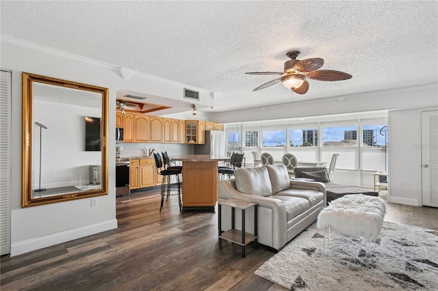 living room with dark wood-style flooring, visible vents, ceiling fan, and a textured ceiling