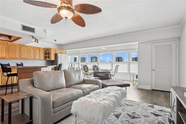 living room with a healthy amount of sunlight, visible vents, dark wood-style flooring, and ceiling fan